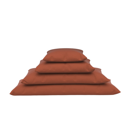Four burnt orange lumbar pillow stacked on a white background.